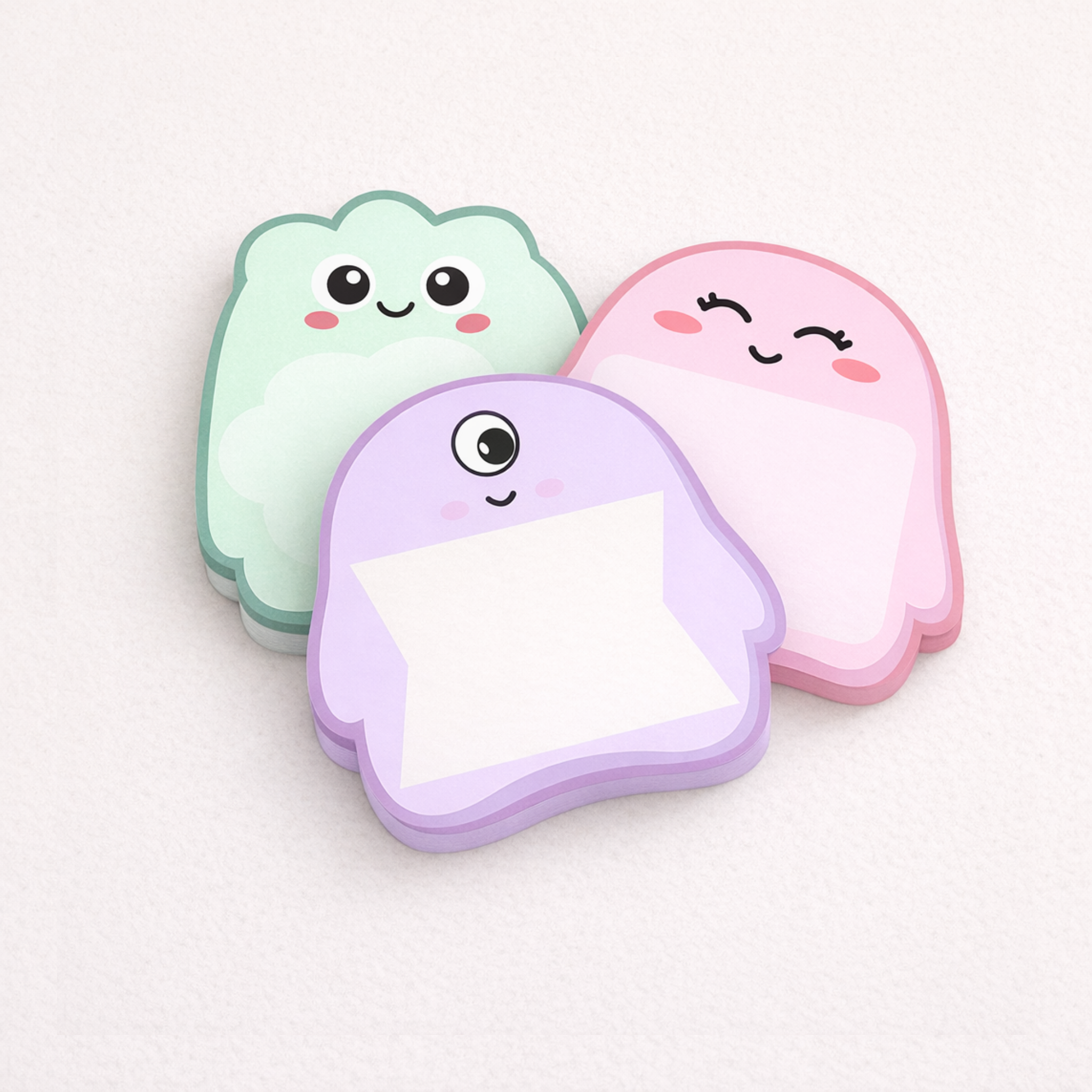 Three cute ghost-shaped sticky notes in pastel colors on a light background